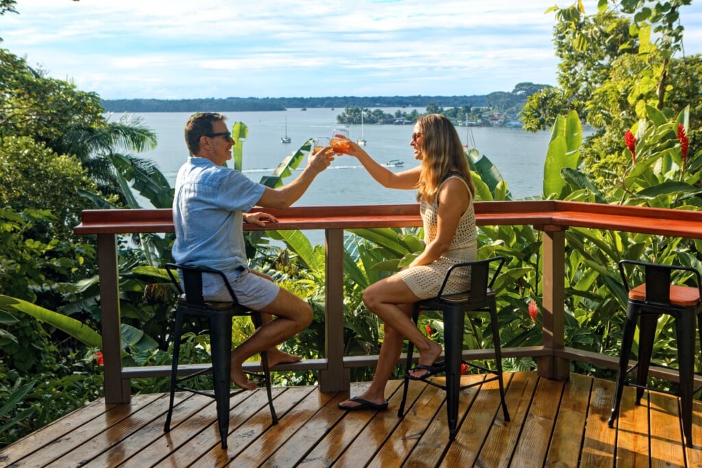 Couple toasting at the deck bar overlooking the bay, The Lodge at Punta Rica