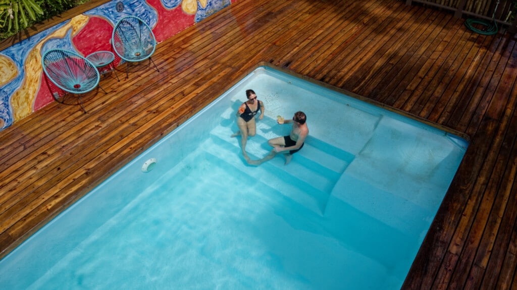 Two guests swimming in the pool beside the mural deck